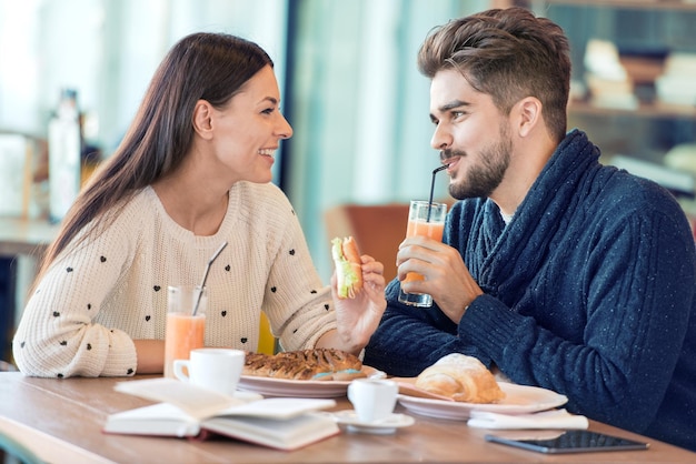 Casal desfrutando de refeição sentado à mesa de café