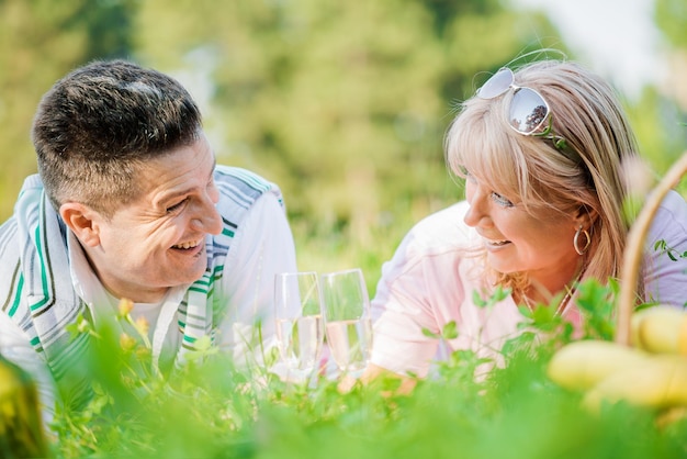 Casal desfrutando de vinho branco no piquenique