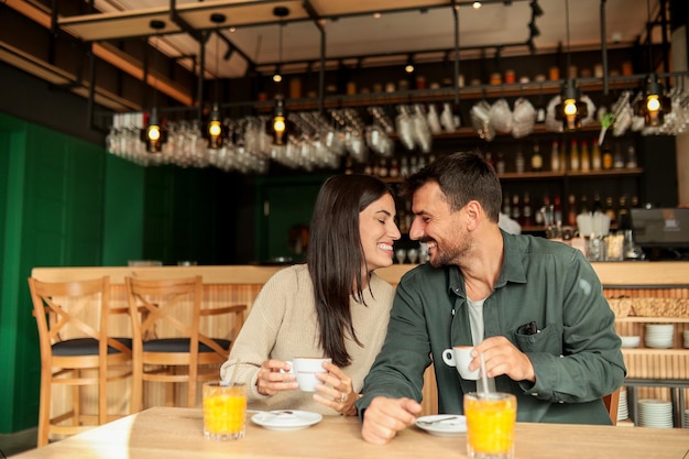 Casal desfrutando em um café aconchegante com bebidas quentes e risadas em um ambiente moderno vibrante em uma tarde ensolarada