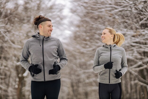 Casal desportivo correndo juntos em um dia de inverno nevado na natureza. fitness ao ar livre, fitness de inverno, hábitos saudáveis