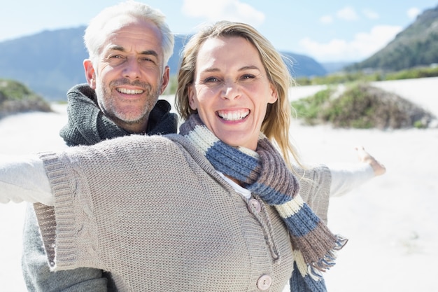 Casal despreocupado de pé na praia com roupas quentes