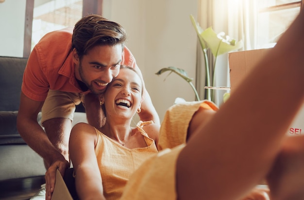 Foto casal divertido se mudando para a primeira casa juntos se divertindo e aproveitando sua liberdade jovens recém-casados curtindo a nova casa brincando e se sentindo animados proprietários alegres brincando enquanto desempacotam