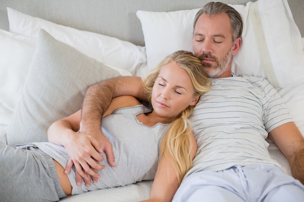 Casal dormindo na cama no quarto