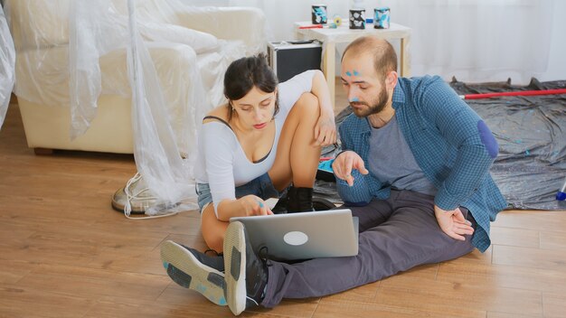 Casal durante a renovação em casa usando o laptop. redecoração de apartamento e construção de casa durante a reforma e melhoria. reparação e decoração.