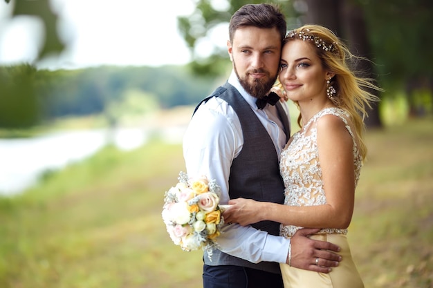 Casal elegante de recém-casados felizes posando no parque no dia do casamento. Casal perfeito, noiva, noivo