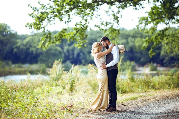 Casal elegante de recém-casados felizes posando no parque no dia do casamento. casal perfeito, noiva, noivo