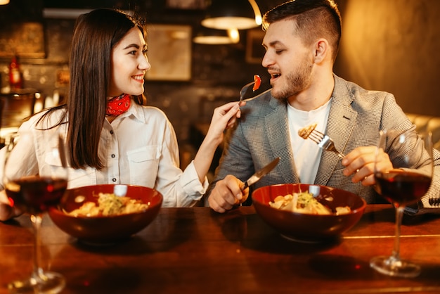 Casal em balcão de bar de madeira, jantar romântico