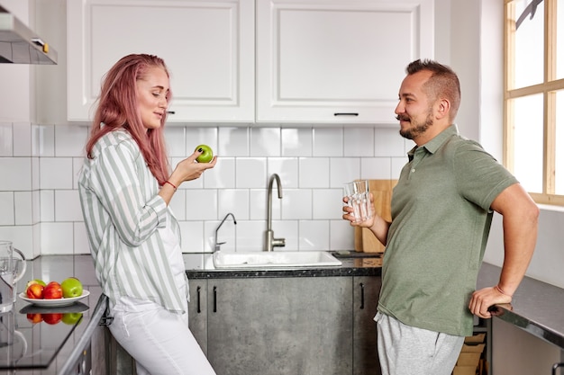 Casal em casa no fim de semana, lindo casal na cozinha leve e moderna, curtindo passar o tempo juntos, conversando