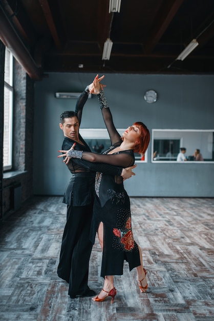 Casal em fantasias no treinamento de dança ballrom em sala de aula. Parceiros masculinos e femininos em pares profissionais dançando no estúdio