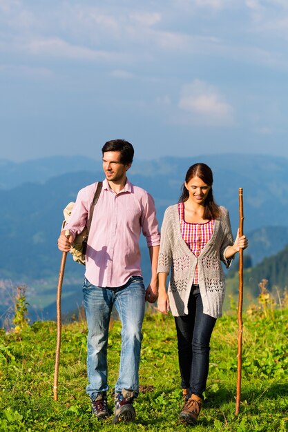 Casal em férias de caminhada fitness no cume da montanha ou pastagem alpina nos Alpes