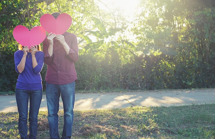 Foto casal em forma de coração enquanto está de pé no parque