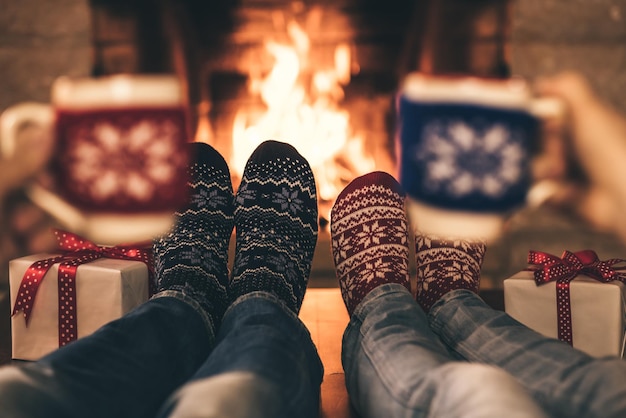 Casal em meias de Natal perto da lareira. Homem e mulher se divertindo juntos. Pessoas relaxando em casa. Conceito de férias de inverno e Natal