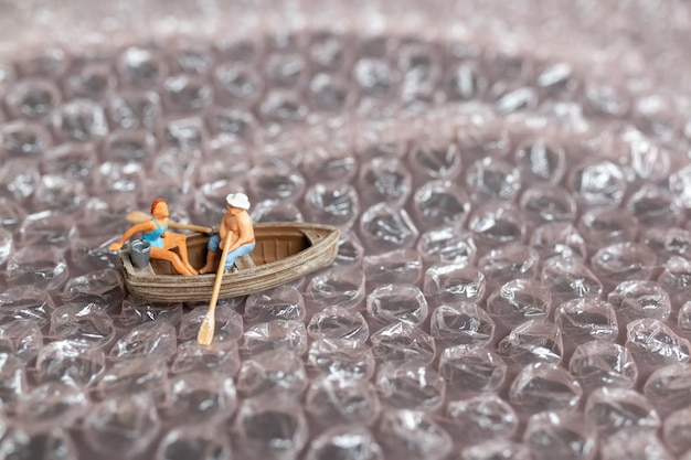 Casal em miniatura com barco navegando na bolha rosa