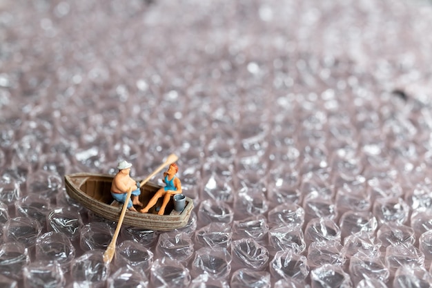 Casal em miniatura com barco navegando na bolha rosa