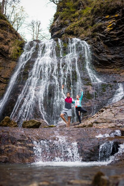 Casal em pé em uma árvore faz exercícios de equilíbrio matinal no majestoso ambiente natural