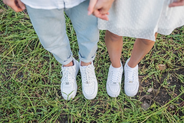 Casal em pé no campo de grama. pés e sapatos do jovem casal.