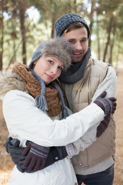 Casal em roupas de inverno abraçando na floresta