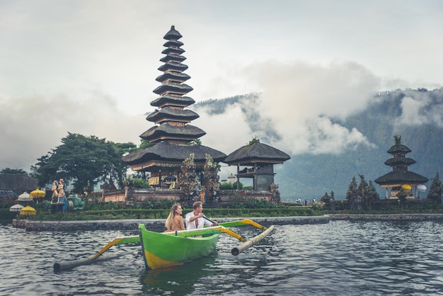 Casal em um barco de apoio no lago contra o templo