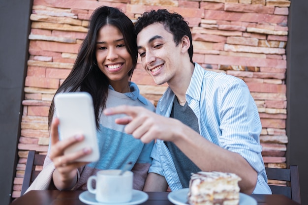 Foto casal em um café moderno, curtindo o tempo juntos navegando no telefone.