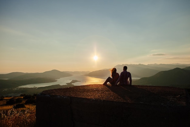 Casal em uma estrutura construída contra o céu durante o pôr do sol