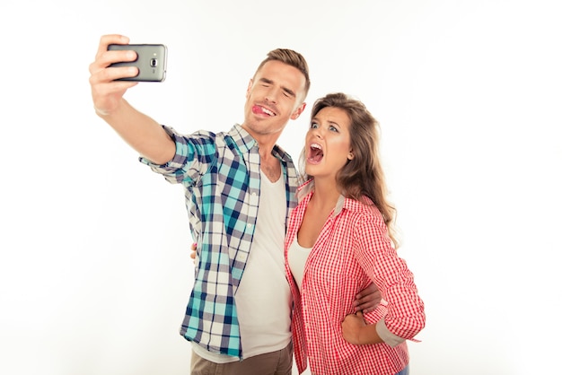 Casal engraçado e alegre apaixonado fazendo selfie foto com smartphone