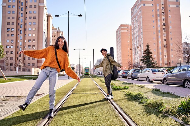 Casal equilibrando nos trilhos do trem ou bonde enquanto ri do conceito de juventude e lazer