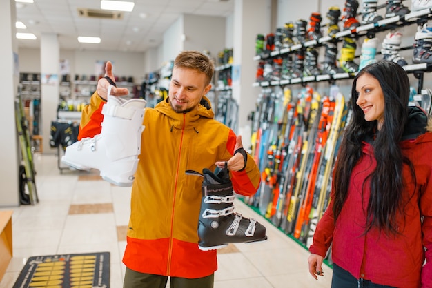Casal escolhendo botas de esqui, compras, loja de esportes