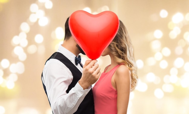 casal escondido atrás de um balão em forma de coração vermelho