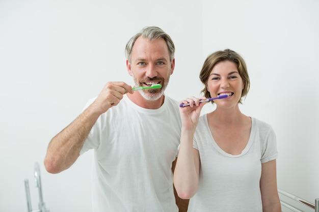 Casal escovando os dentes com escova em casa