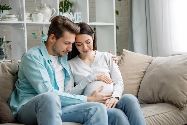 Casal esperando um bebê enquanto marido acaricia a barriga de sua mulher grávida