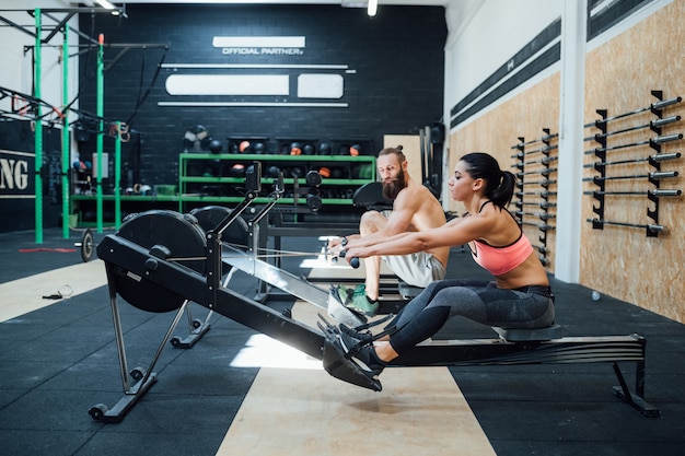 Casal esportivo cross fit treinamento remo na máquina de remador