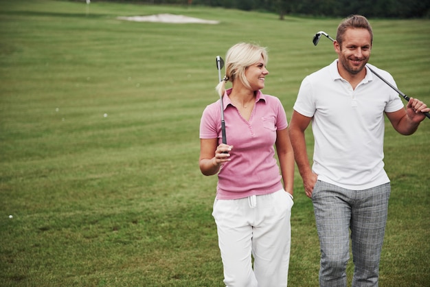 Casal esportivo jogando golfe em um campo de golfe, eles ficam no próximo buraco