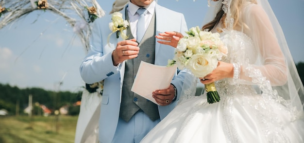 Casal está caminhando na cerimônia de casamento ao ar livre Noiva e noivo de braços dados Arco com flores