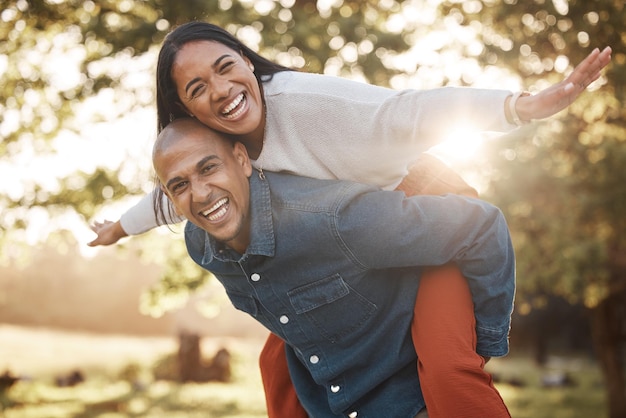 Casal estaciona e feliz com retrato nas costas e jogo de avião em férias na natureza e união no verão homem mulher e brincalhão na liberdade do quintal e férias perto de árvores com amor no sol