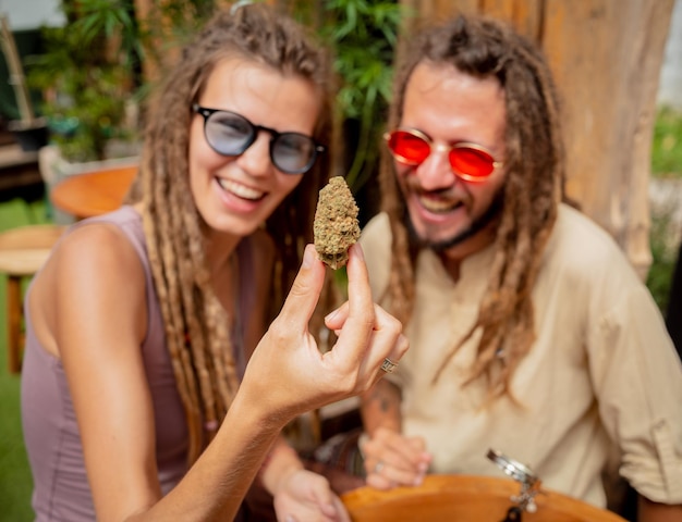 Casal estilo hippie examina articulações e brotos de maconha medicinal