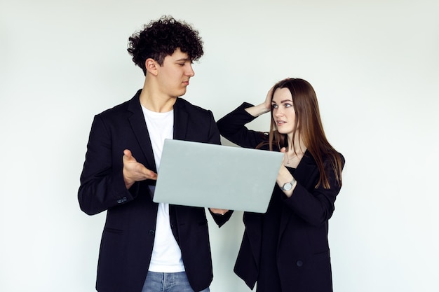 Casal estiloso posando com laptop moderno e vestindo elegantes blazers pretos e acessórios para homens