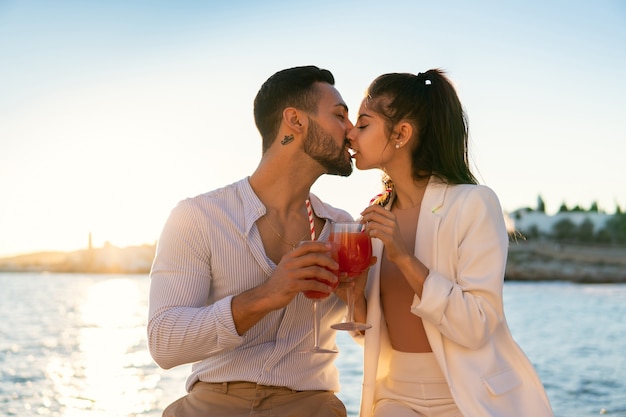 Casal étnico apaixonado se beijando à beira-mar