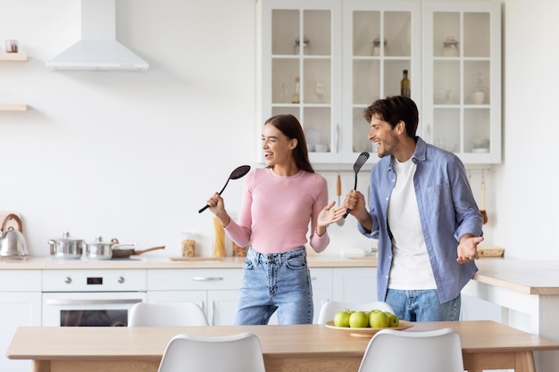 Casal europeu do milênio atraente e engraçado satisfeito se diverte cantando no microfone imaginário