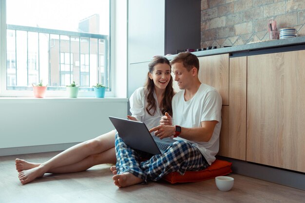 Casal falando enquanto faz compras online sentado no chão