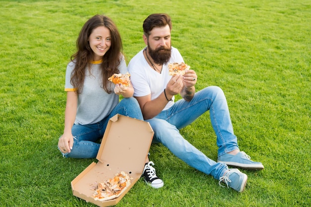 Casal faminto fome família fim de semana casal apaixonado namoro casal feliz comendo pizza Comida saudável fast food homem barbudo hipster e adorável garota come pizza piquenique de verão na grama verde Dieta