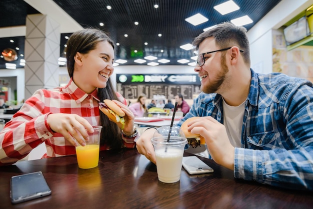 Casal faz uma pausa para fazer compras comem hambúrgueres no café do shopping