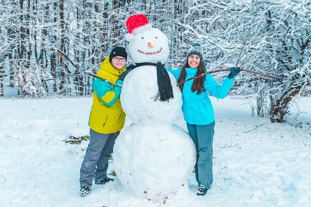 Casal fazendo boneco de neve no conceito de dia de inverno congelado