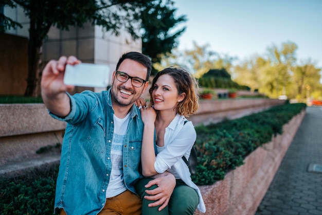 Casal fazendo selfie ao ar livre.