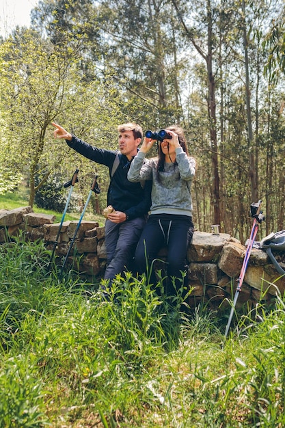 Casal fazendo trekking olhando com binóculos