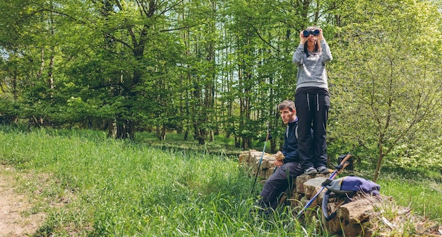 Casal fazendo trekking olhando com binóculos