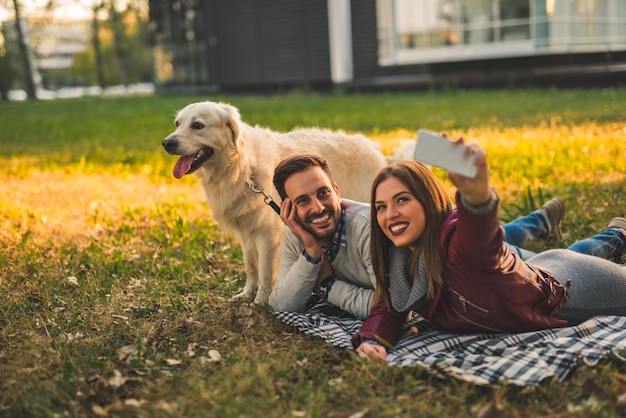 Casal fazendo uma selfie com um cachorro