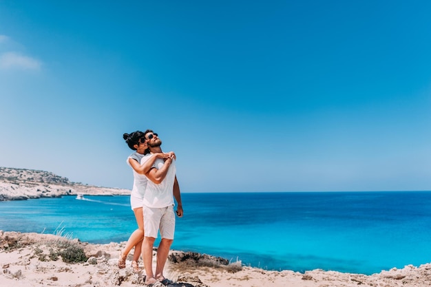 Casal feliz à beira-mar. Homem e mulher se abraçando na praia. Amantes da lua de mel. Homem e mulher na ilha. Casal apaixonado de férias. Passeio marítimo. Viagem de lua de mel. Casal apaixonado na lagoa azul