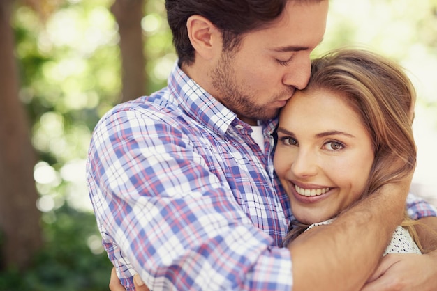 Casal feliz abraça união ou beijo na testa no dia do amor dia dos namorados ou romance pausa na natureza estacione ou relaxe jardim Sorriso de mulher ou homem beijando a cabeça em confiança abraço de segurança ou obrigado apoio