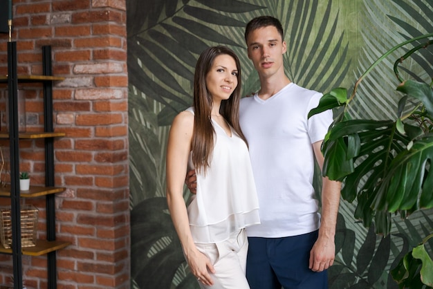 Casal feliz abraçando e olhando para a câmera em pé contra um fundo verde