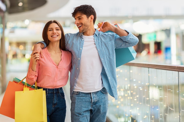 Casal feliz abraçando fazendo compras caminhando juntos no hipermercado